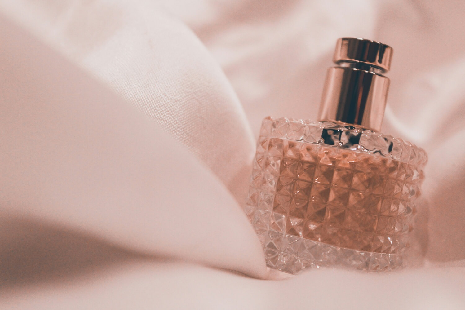 Flakon perfum położony na miękkim, białym materiale